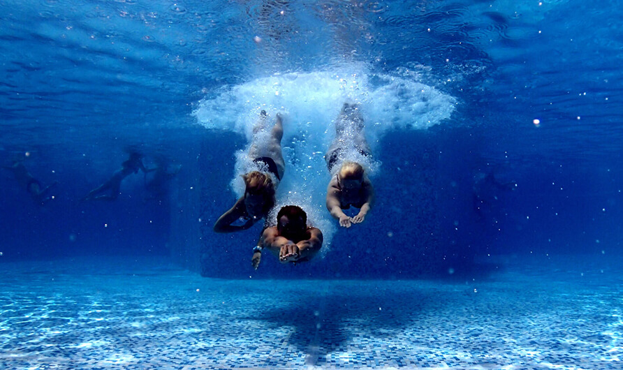 Drie mensen onderwater in een zwembad